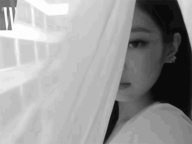 a black and white photo of a woman covering her face with a white cloth .