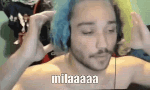 a shirtless man with blue hair and headphones is making a funny face .