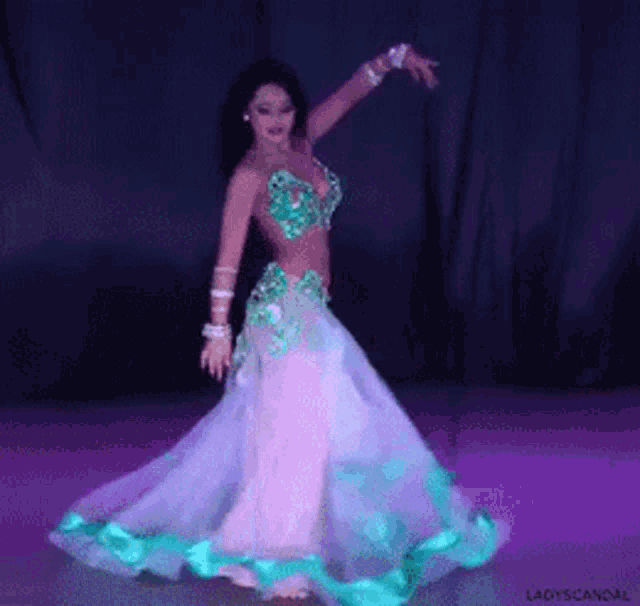 a woman in a green and white dress is dancing in a dark room