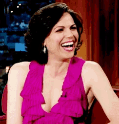 a woman in a pink dress is laughing with her mouth wide open