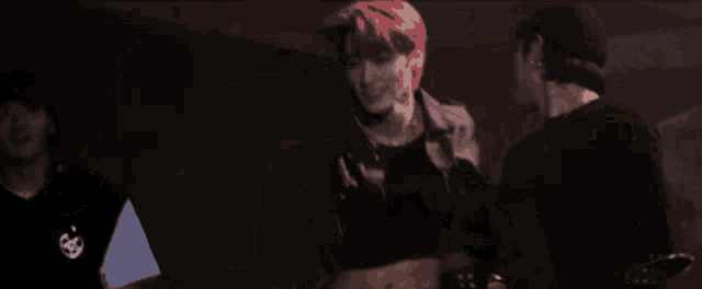 a man with red hair is standing next to a man in a black shirt in a dark room .