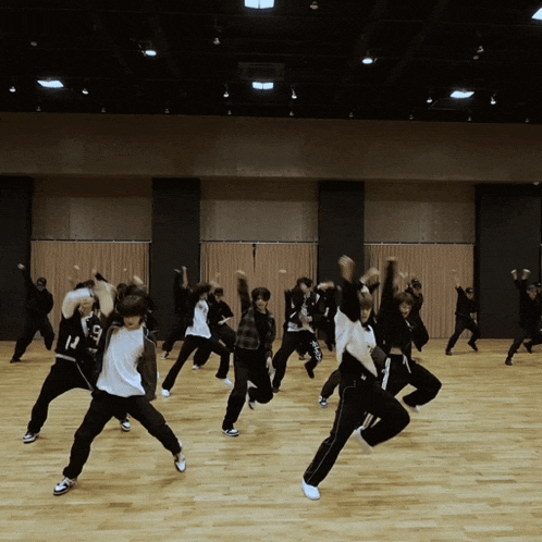 a group of young people are dancing in a room and one of them has the number 13 on his back