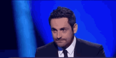 a man in a suit and tie is looking at the camera
