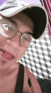 a man wearing glasses and a baseball cap is taking a selfie