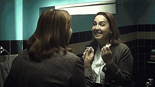 a woman is looking at herself in a bathroom mirror and smiling
