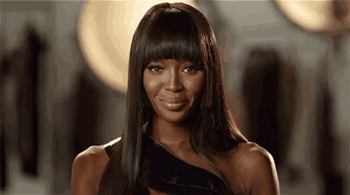 a woman with long black hair and bangs is smiling for the camera .
