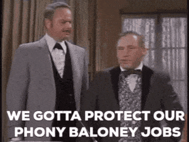 two men in suits and bow ties are standing next to each other in a room and talking .