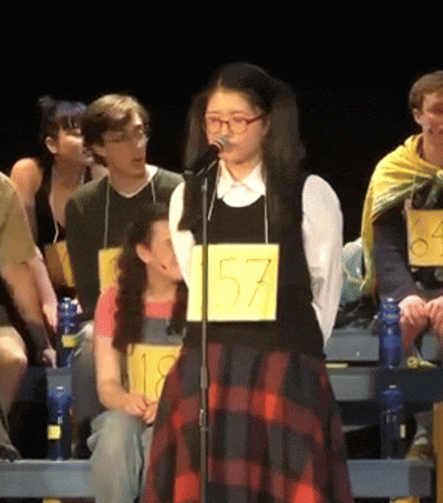 a girl singing into a microphone while wearing a number 57 tag