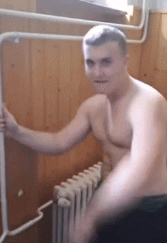 a shirtless man is standing next to a radiator in a room