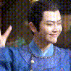 a man in a blue robe is waving his hand .