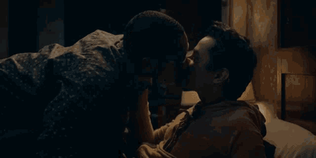 two men are kissing each other on a bed .