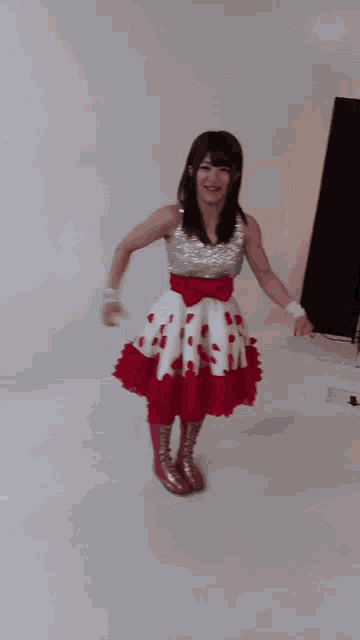 a woman in a red and white dress is standing in a room