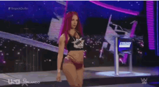 a woman in a bikini is dancing on a stage in front of a purple sign .