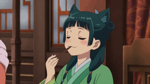 a girl with a cat ear on her head is eating something with chopsticks
