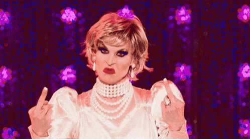 a drag queen is making a funny face while wearing a white dress and pearls .