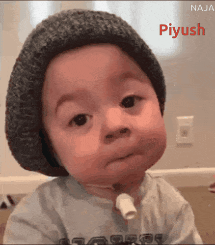 a baby wearing a knitted hat with the name piyush on the bottom right
