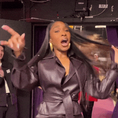 a woman wearing a brown leather jacket is making a funny face