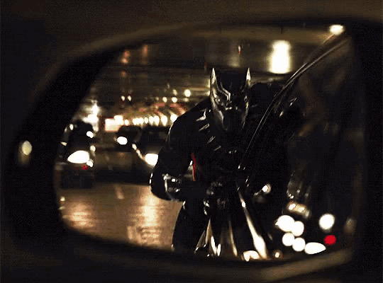 a man in a black suit is standing in a dark tunnel