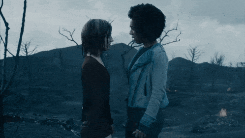 two women are kissing in a dark room with a blue background