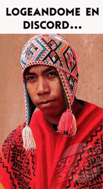 a man wearing a colorful hat and a red poncho is looking at the camera .
