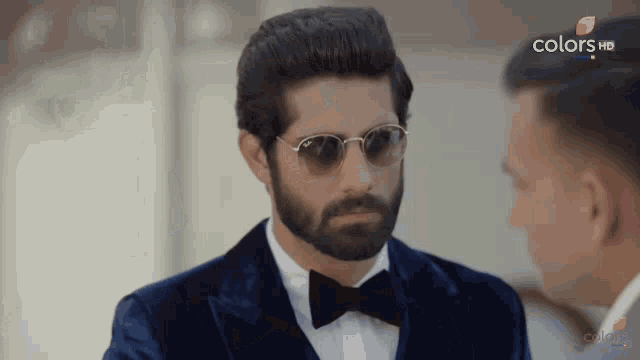 a man with a beard wearing sunglasses and a bow tie is on a screen that says colorsvn