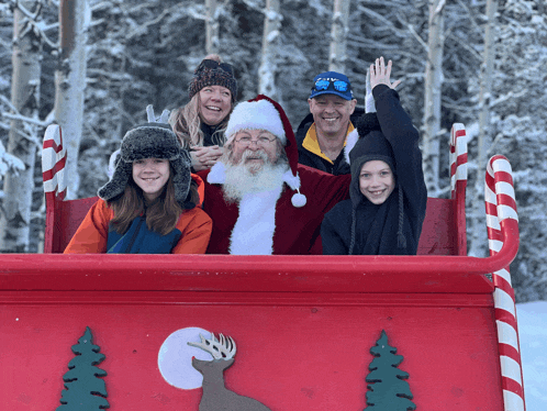 a family posing with santa in a sleigh