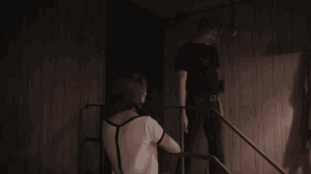 a man and a woman are standing on a set of stairs in a dark room