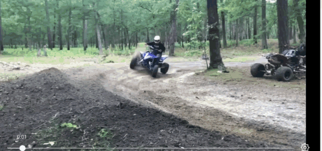a man is riding a four wheeler on a dirt road in the woods ..