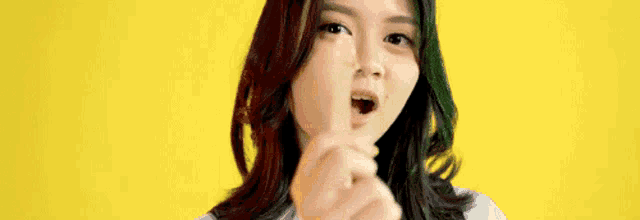 a woman is holding a stick in her mouth and making a shhh gesture .