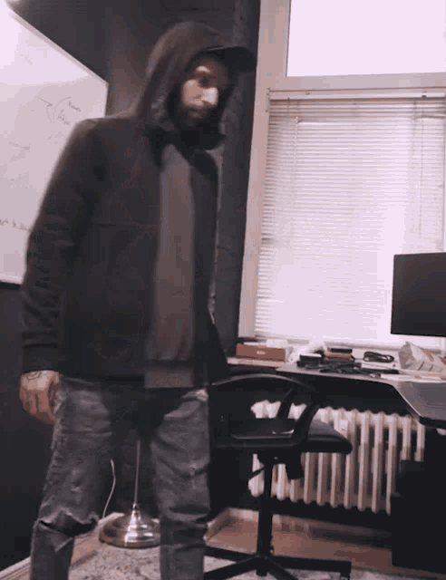 a man in a hooded jacket is standing in front of a white board that says ' i 'm sorry '