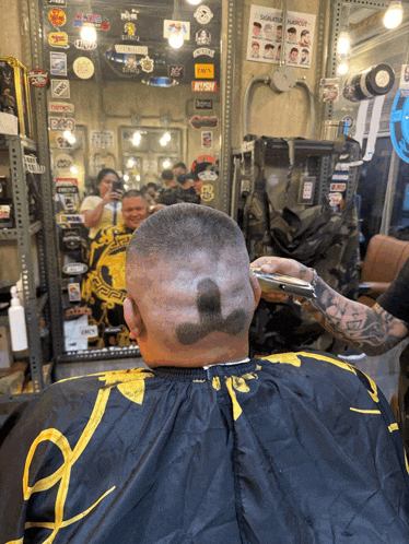 a man is getting his hair cut at a barber shop with a sticker on the wall that says ' a ' on it