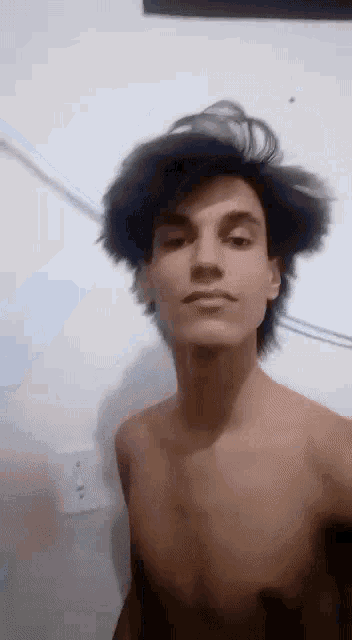 a young man without a shirt is taking a picture of himself .
