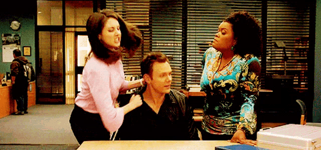 a woman is standing next to a man and a woman is standing next to a table .