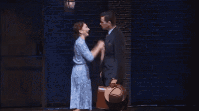a man and a woman are standing next to each other on a stage and laughing .