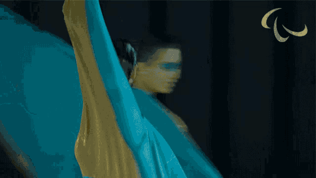 a woman in a blue dress is dancing in front of a black background