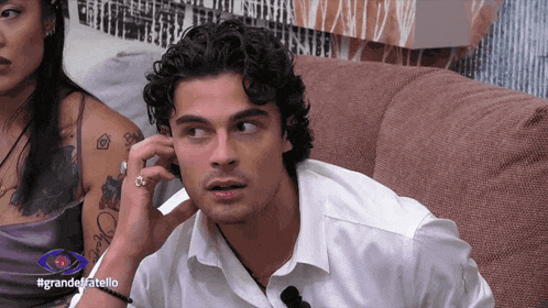 a man sitting on a couch talking on a cell phone with the hashtag grande fratello