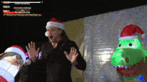 a man wearing a santa hat is standing next to a stuffed dinosaur