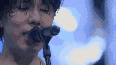 a close up of a person singing into a microphone on stage .