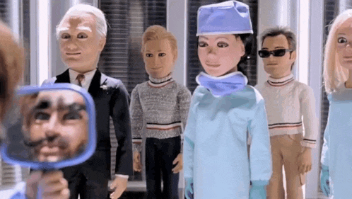 a group of cartoon characters are standing next to each other and one of them is looking at his reflection in a mirror .
