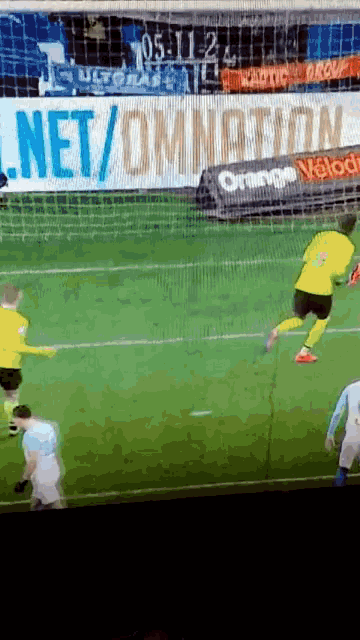 a soccer game is being played in front of a banner that says net / omnation