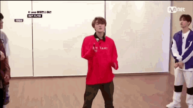 a man in a red sweater is dancing in front of a white wall .