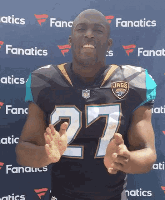 a man wearing a jaguars jersey is clapping his hands