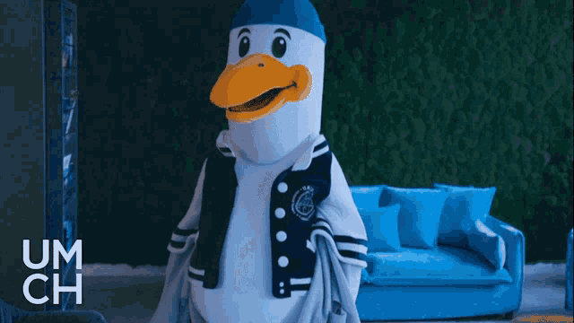 a seagull mascot is standing in front of a blue couch with um ch written on the bottom