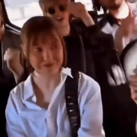 a group of people are sitting in the back seat of a car . one of the people is wearing sunglasses .