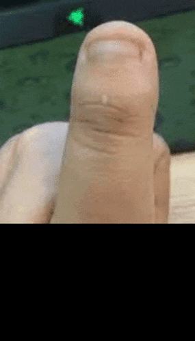 a close up of a person 's thumb with a green light behind it .