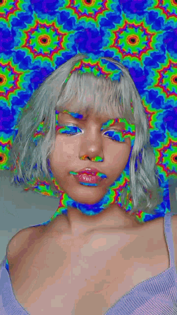 a woman with white hair is standing in front of a colorful kaleidoscope .
