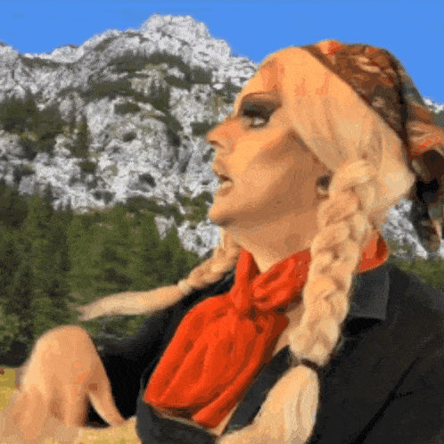 a woman with blonde braids and a red scarf is standing in front of a mountain