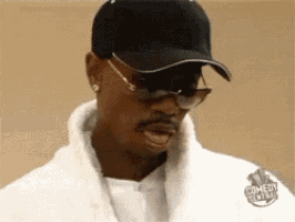 a man wearing a black hat and sunglasses is wearing a comedy central sweatshirt .