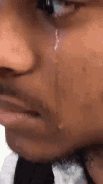 a close up of a man 's face with a tear running down his face .