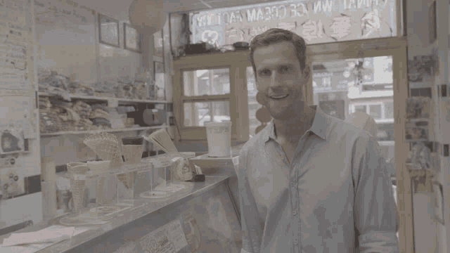 a man in a blue shirt stands in front of a sign that says " ice cream "
